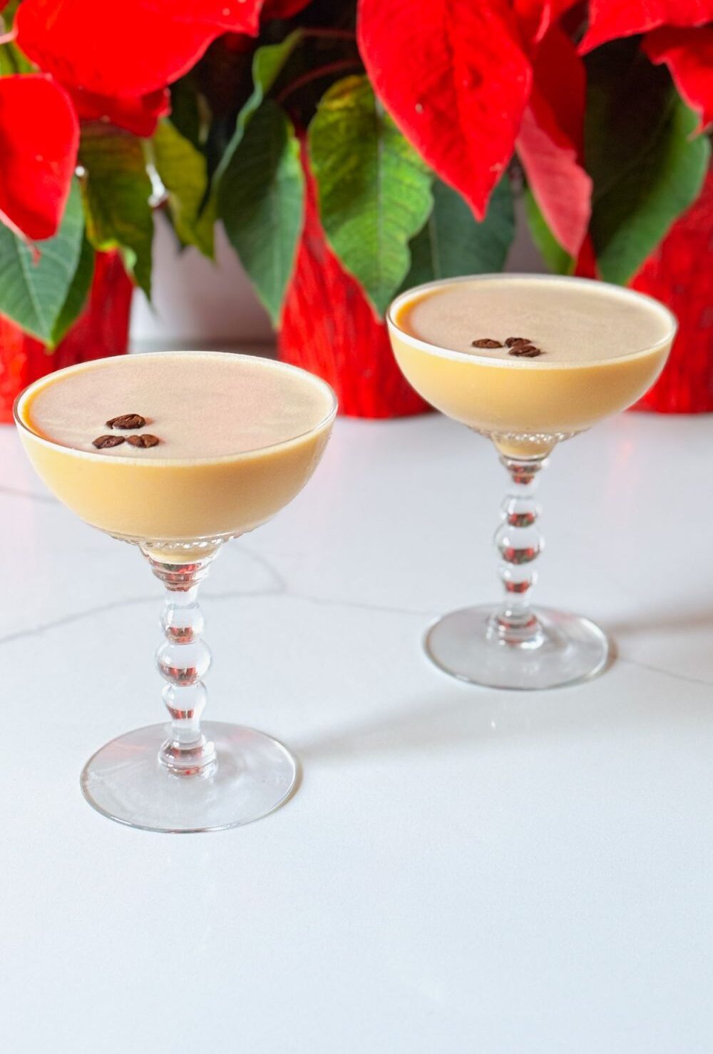 2 eggnog espresso martinis in front of poinsettias