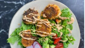 crabcakes on a salad with radishes and chiplte sauce