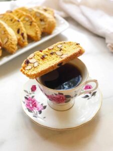 biscotti on a plate and also on the top of a coffee cup with coffee in it