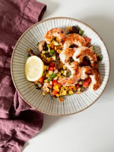 shrimp on a bowl of veggies with a lemon