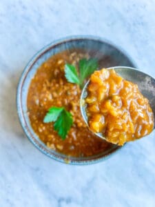 Spicy turkish red lentil soup with a spoon holding some.
