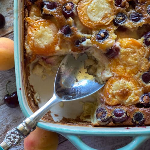 apricot and sweet cherry clafoutis with a spoon taking a scoop out
