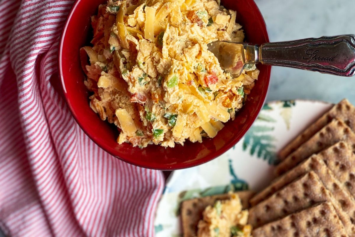 pimento cheese in a red bowl with a plate of crackers