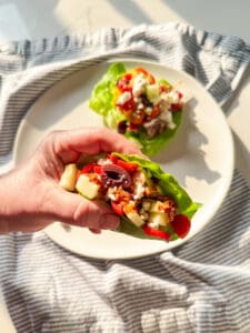 chicken thigh lettuce wrap in a hand and one on the plate