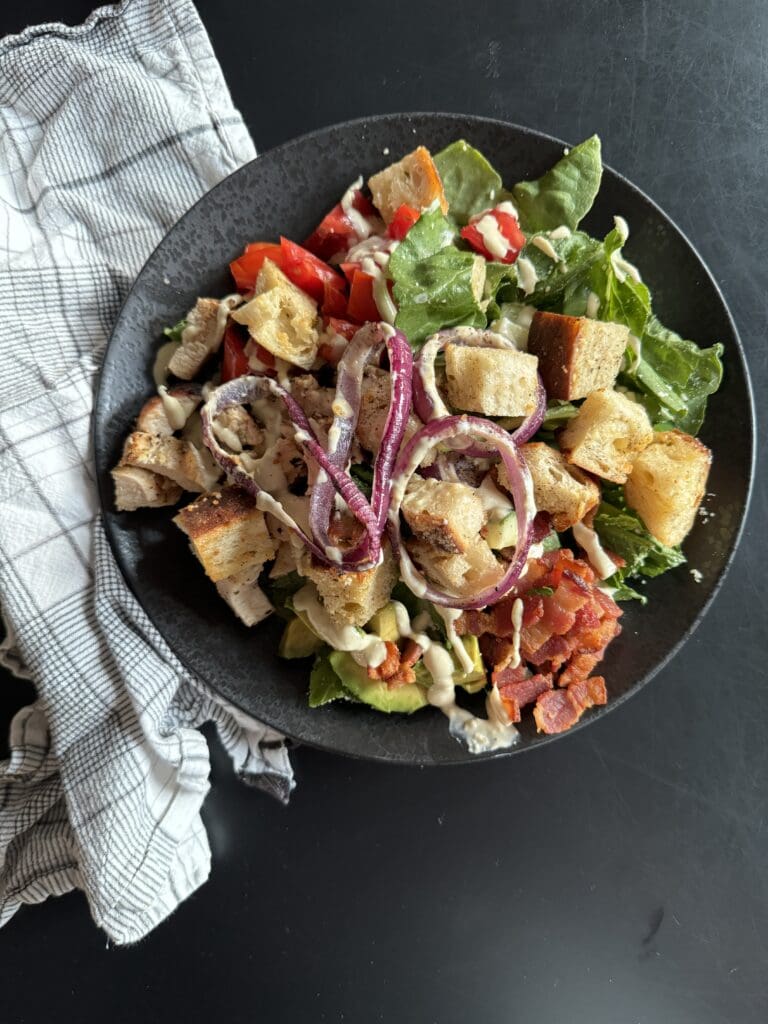 California BLT Caesar salad on a black plate with a napkin