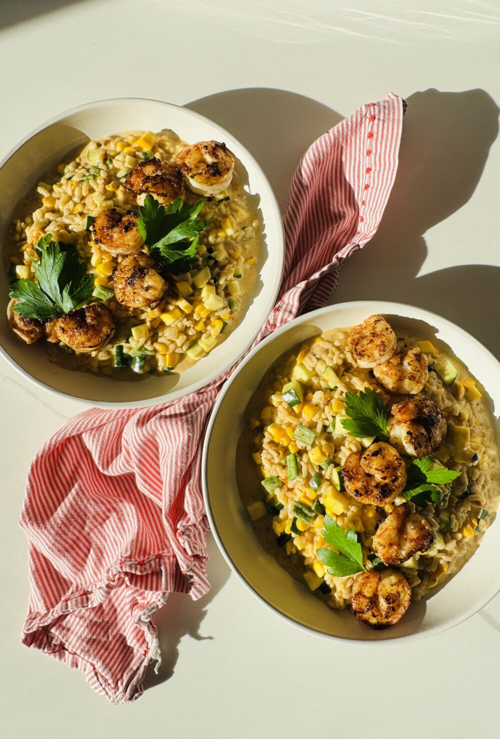 2 bowls of corn and zucchini and summer squash risotto and a red and white napkin