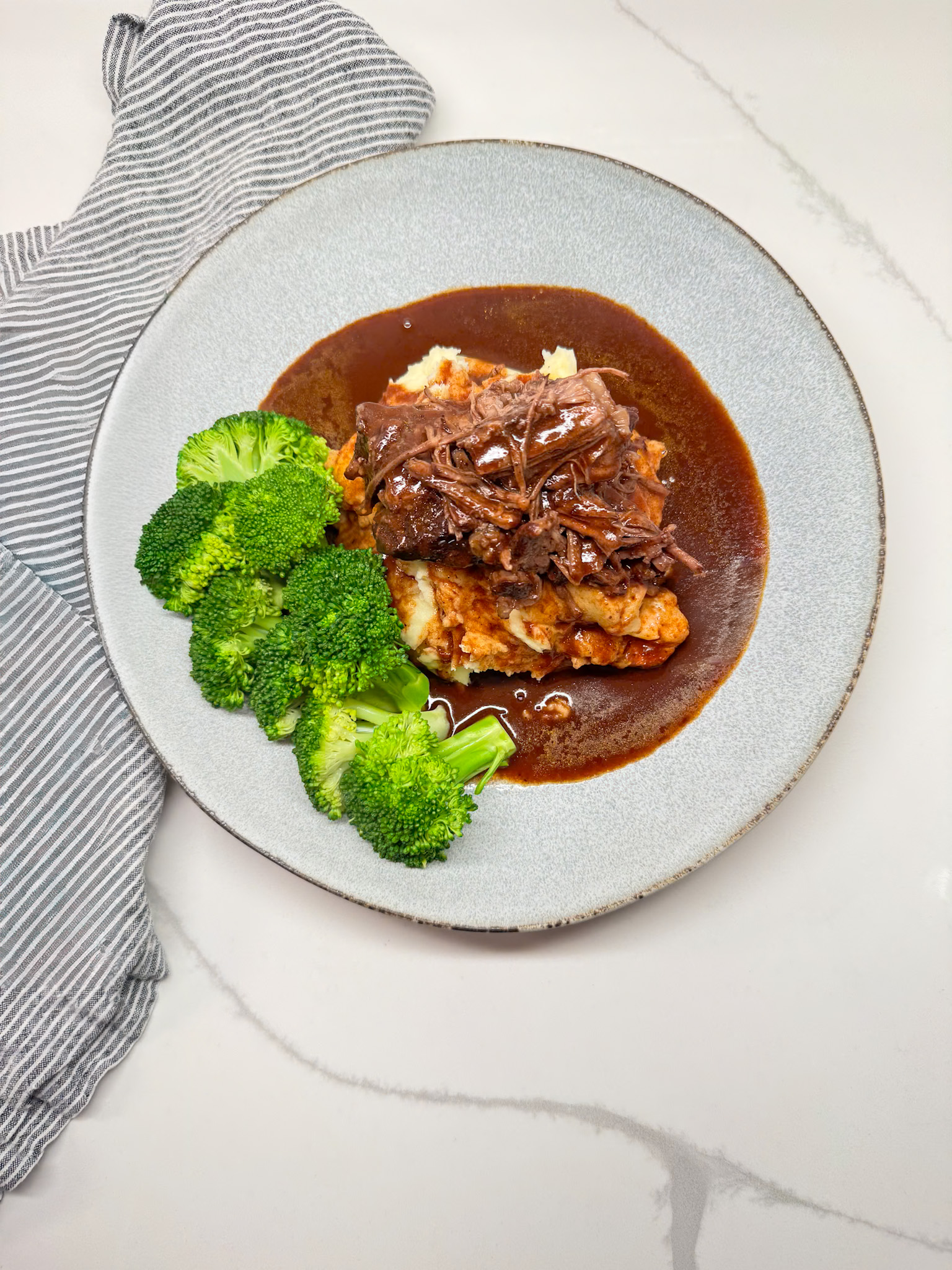 pot roast and gravy on potatoes with broccoli