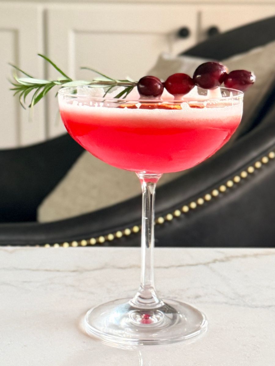 cranberry orange whisky sour in a coupe glass