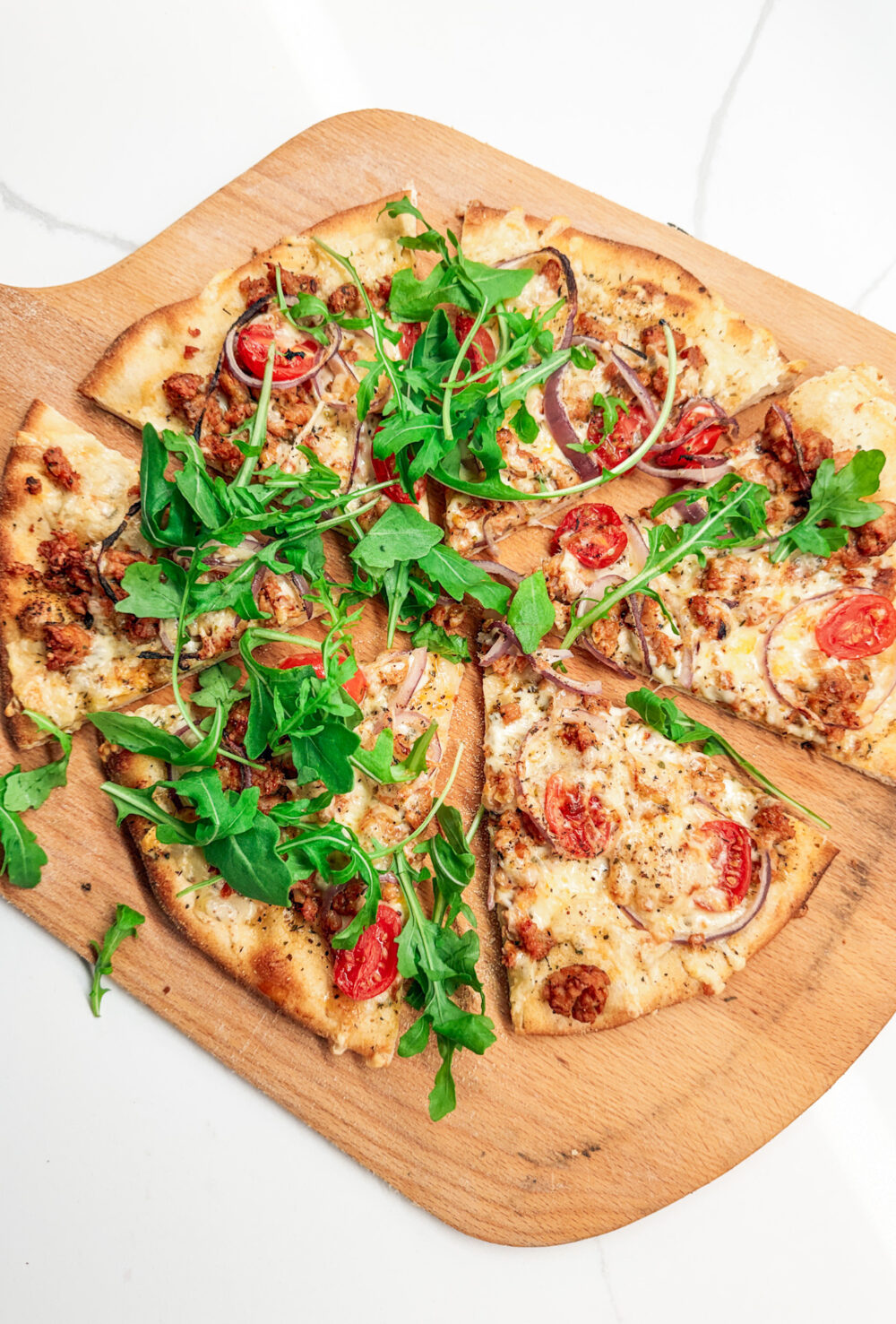 Italian Chicken Sausage pizza sliced with arugula
