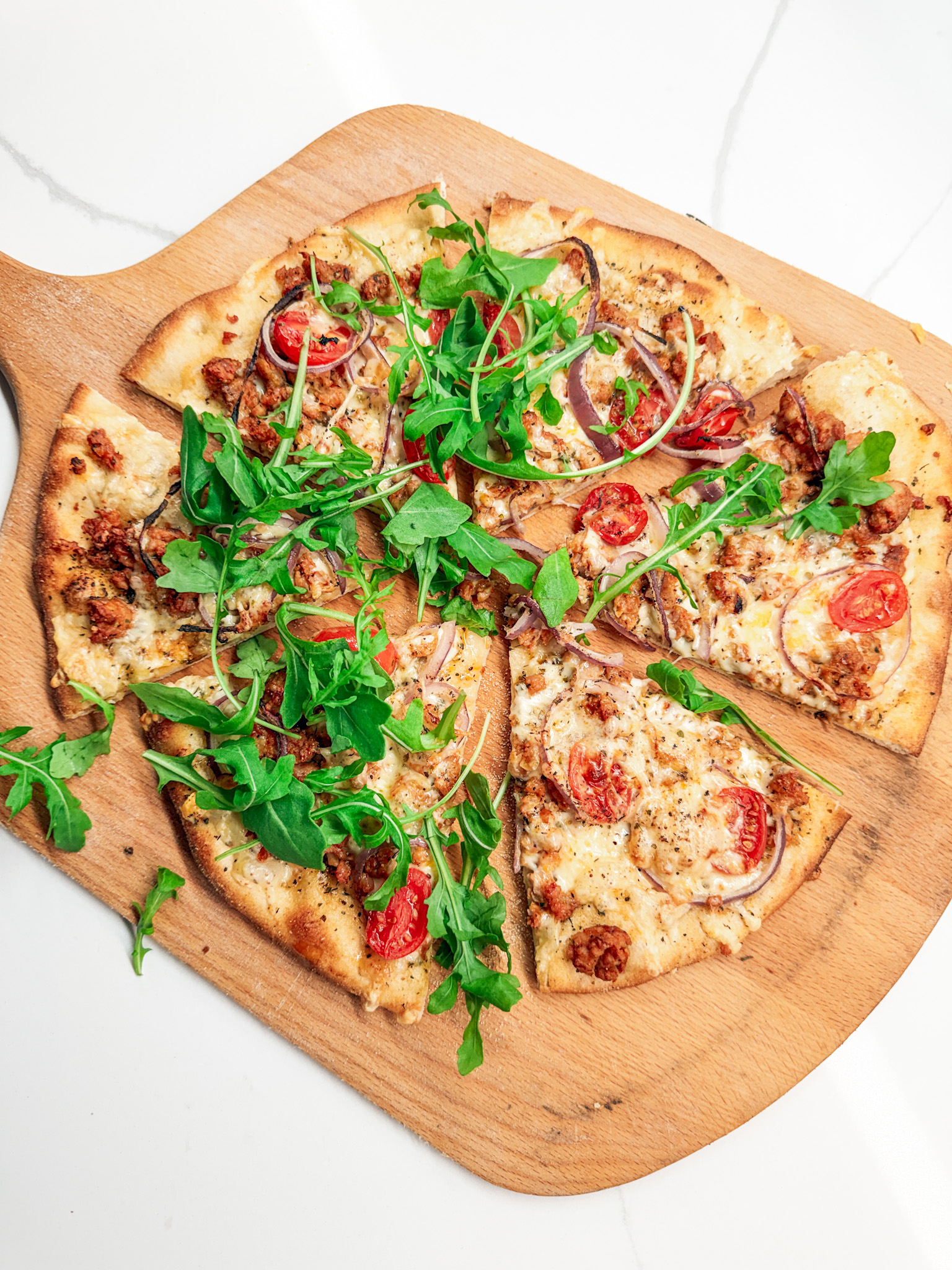 Italian Chicken Sausage pizza sliced with arugula