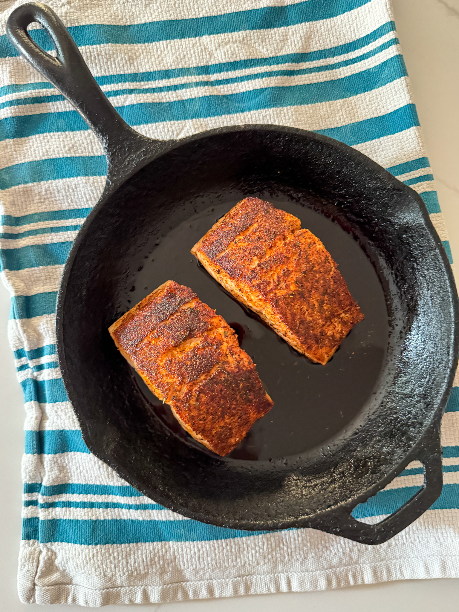 blackened salmon in a skillet on a towel