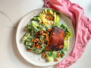 Blackened salmon on a salad with avocado and walnuts
