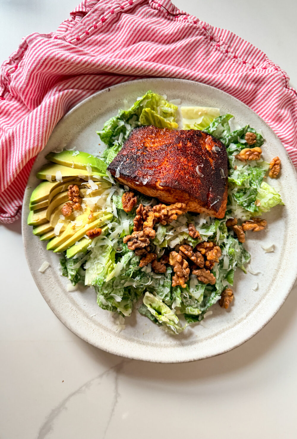 Blackened salmon on a salad with avocado and walnuts