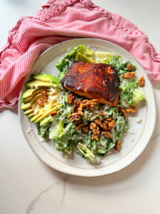 Blackened salmon on a salad with avocado and walnuts