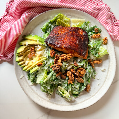 Blackened salmon on a salad with avocado and walnuts