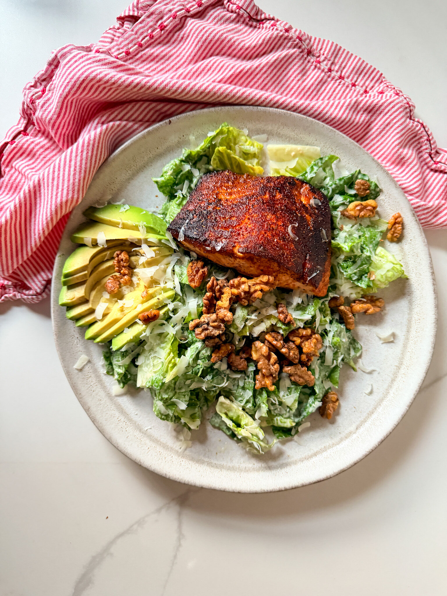 Blackened salmon on a salad with avocado and walnuts