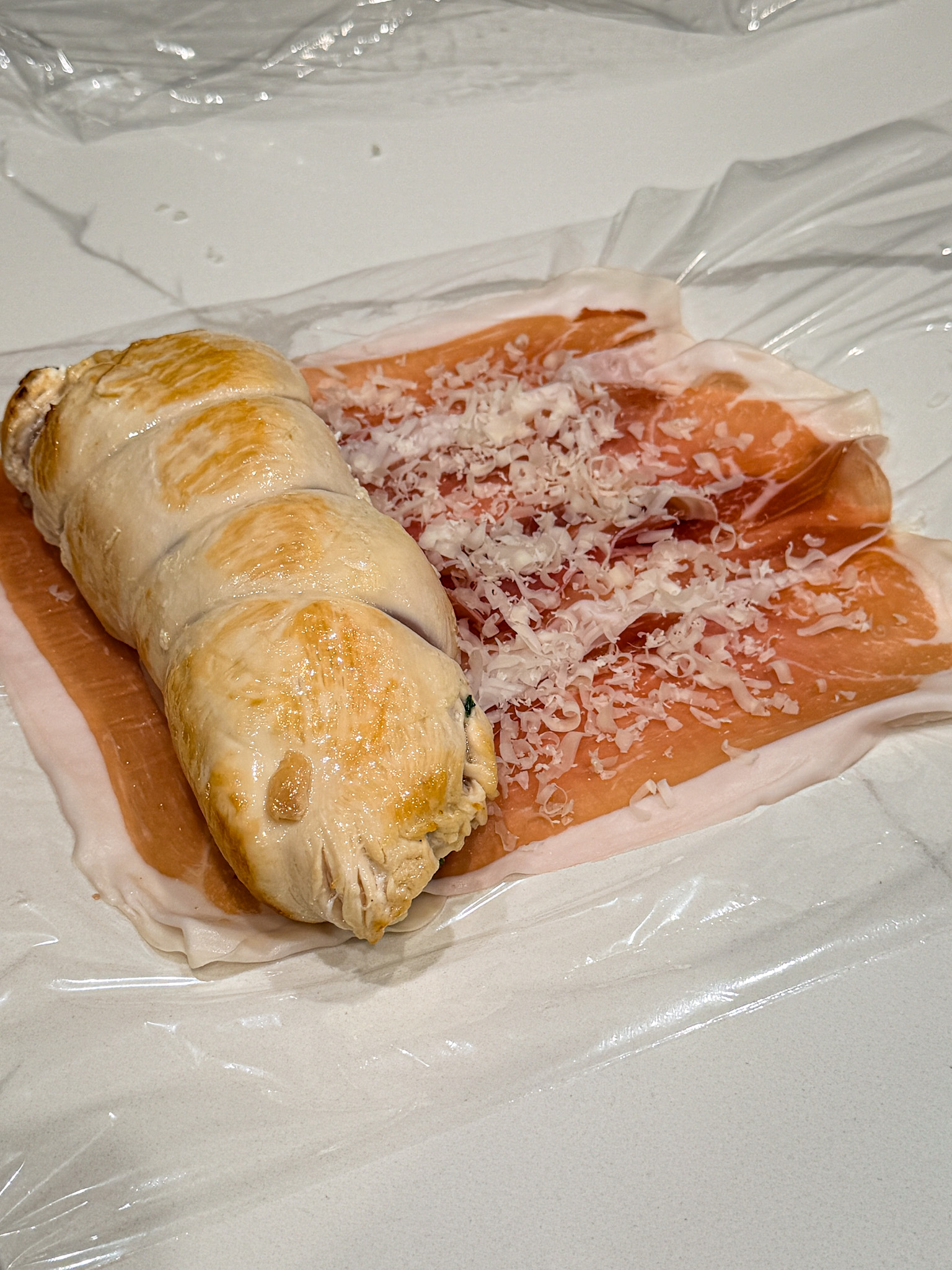 chicken laying on proscuiotto ready to be rolled