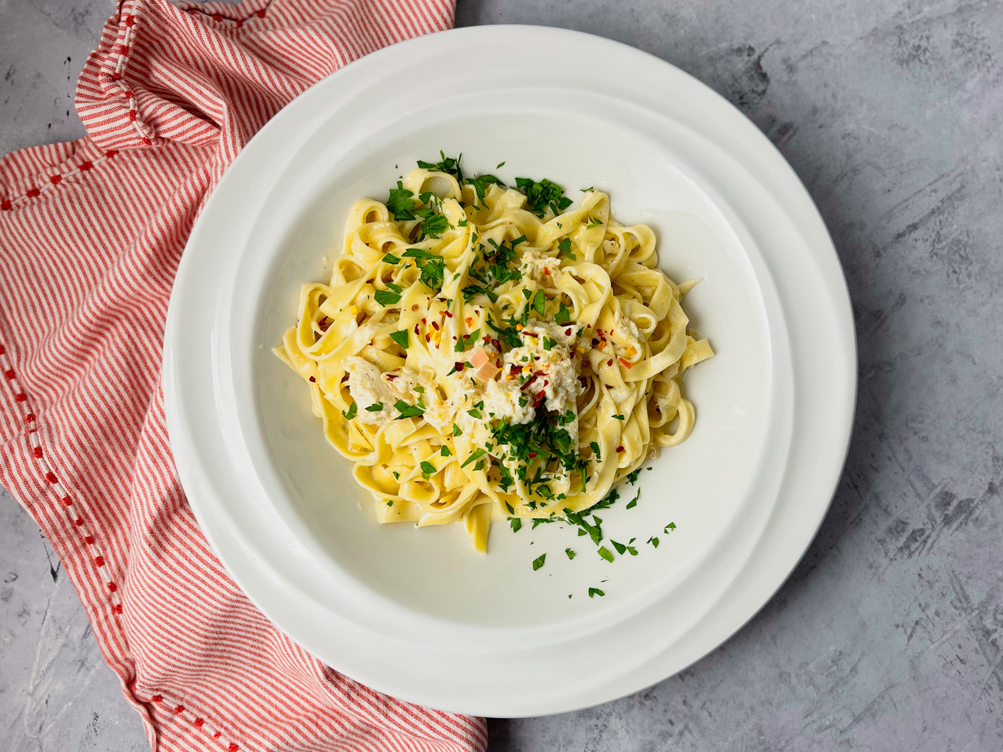 crab fettuccine in a bowl with a red and white napkin
