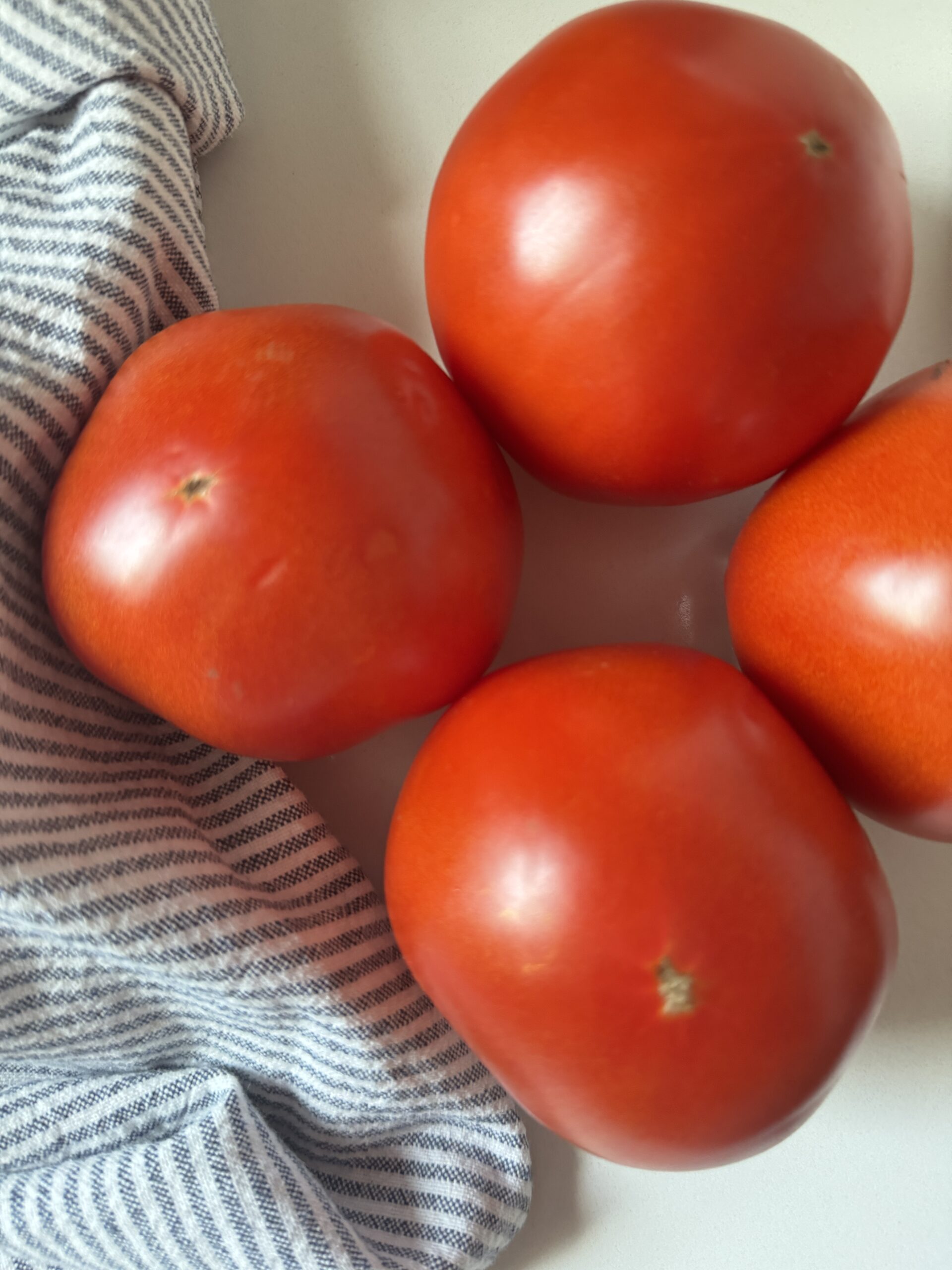 4 tomatoes and a striped napkin