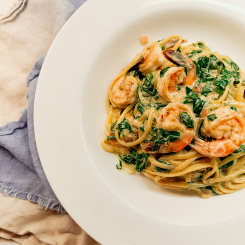 White bowl of shrimp and spinach pasta