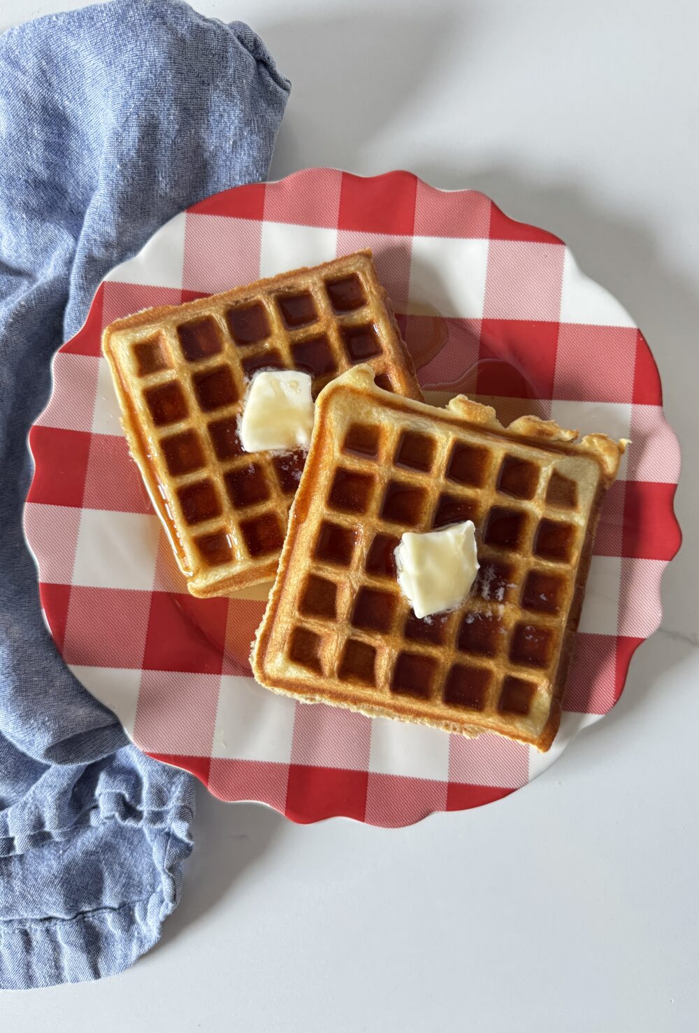 Fluffy Buttermilk Waffles on a red and white plate with a blue napkin